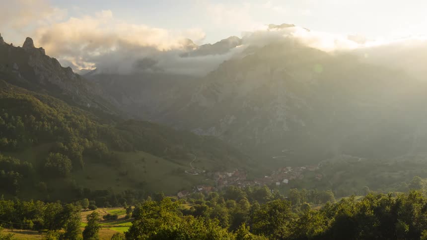 A small housing community sits in a valley surrounded by green mountains