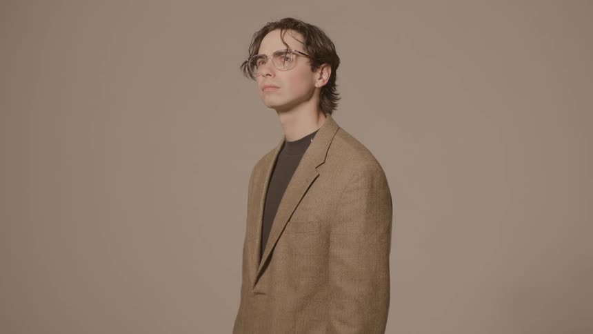 Teenager boy posing with glasses and a formal blazer indoors