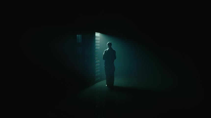 A person Standing In Front Of Server Rack In Dark Data Center