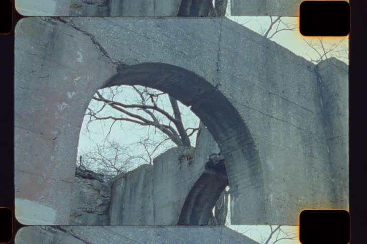 Weathered concrete arch framing bare branches in the background