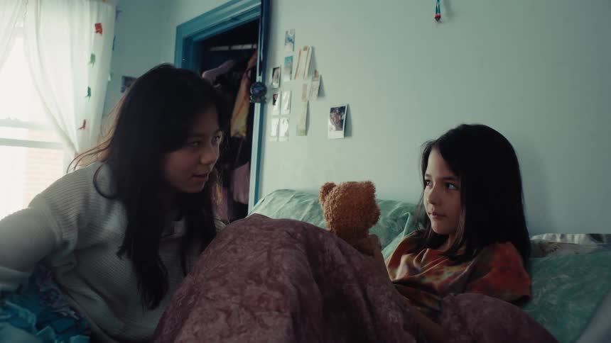 A mother talks with her daughter who is lying on the bed at midday