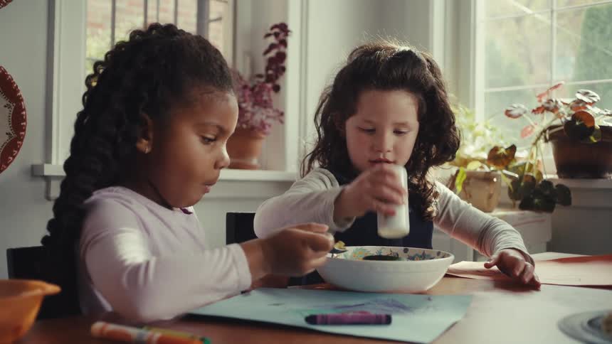 Two kids putting salt on some food