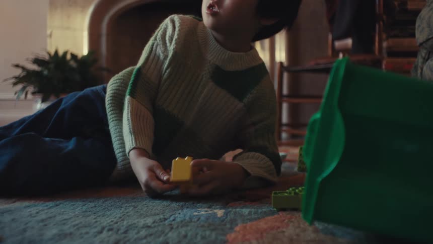 Child lying on carpeted floor playing with colorful blocks in cozy home setting
