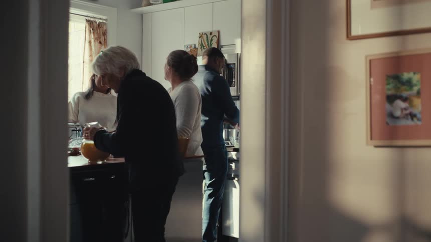 Family gathered in a kitchen with a woman carrying a pitcher of juice