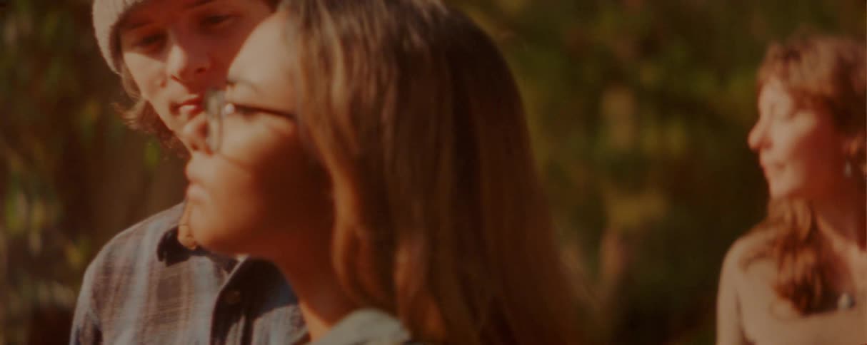 Two young couples stand in the woods at sunset each pair holding hands as they talk together in the warm fading light