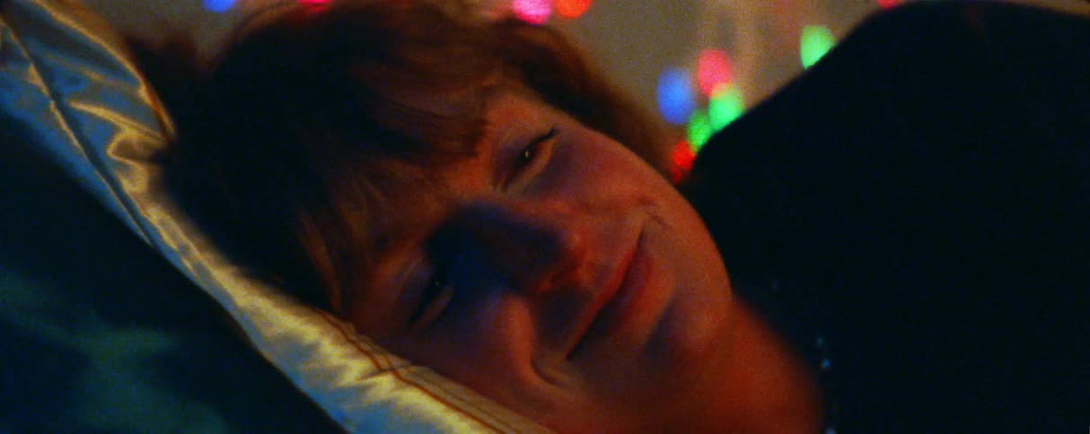 The woman talks and smiles while resting on the pillows