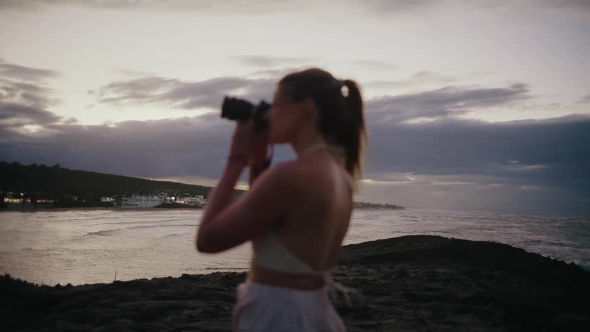 Female photographer photographing a beach landscape at sunset