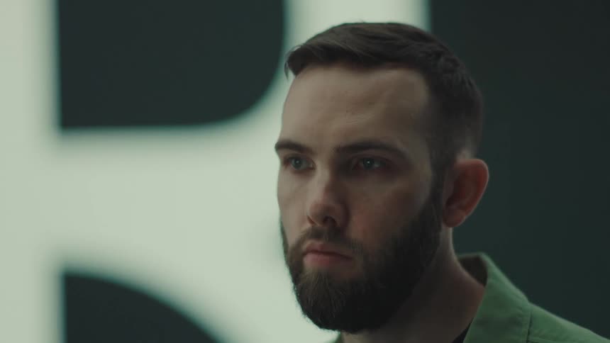 The man is looking at his computer monitor at the desk