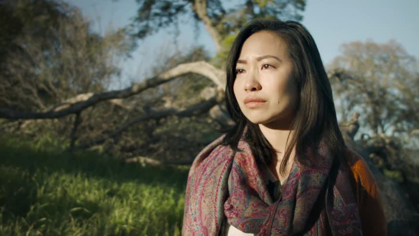Woman stands in the woods crying