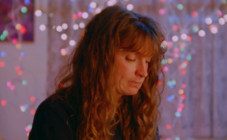 Woman with long hair looks downward indoors with defocused colorful lights in the background
