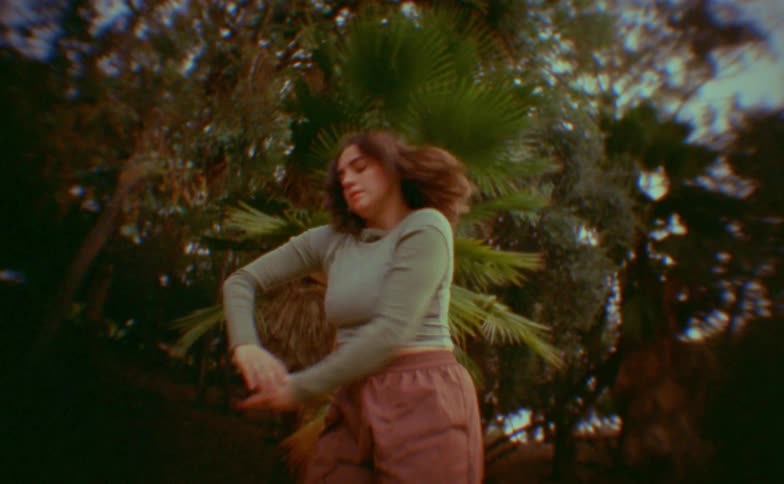 Teenager girl making dance moves in front of trees outdoors during day time