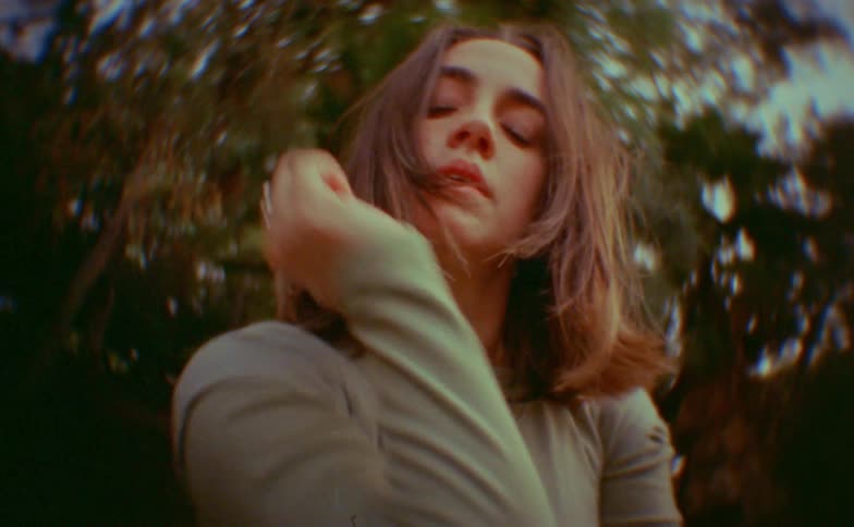 Teenager girl outdoors making dance moves with her arms and head with trees on the background
