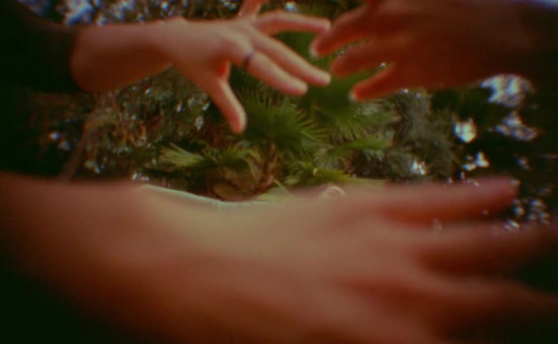 Teenager girl dancing while other dancers move their hands around her next to a grove outdoors during day time