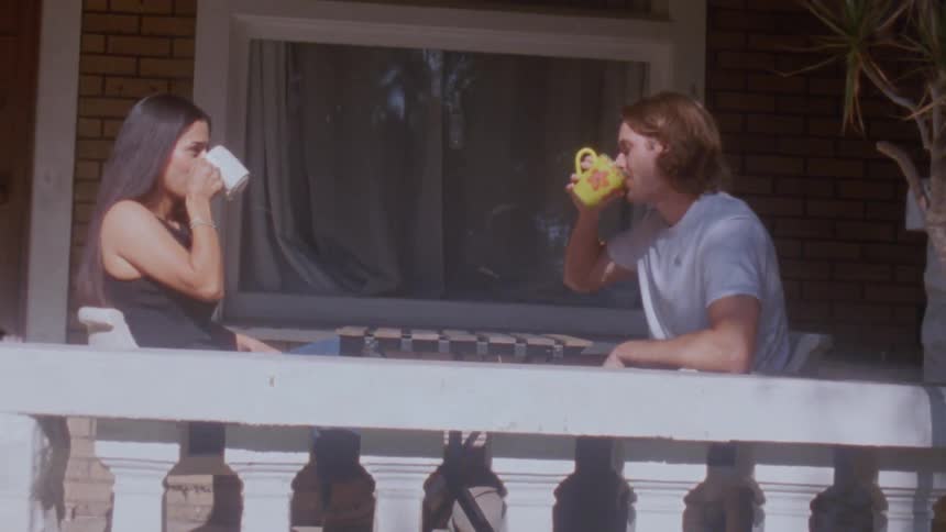 A young couple drinking together at a table outdoors at a balcony during daytime