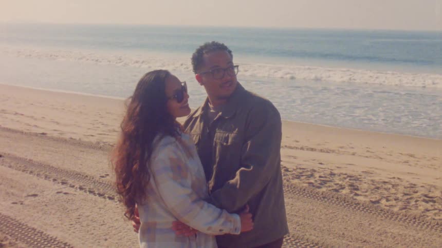 Man and woman standing together on the beach as waves roll in to shore