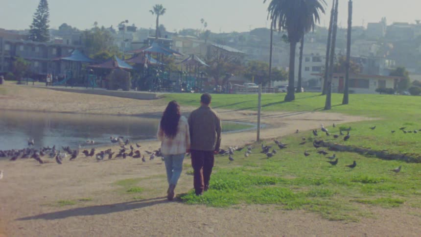 A man and woman walking near a lake