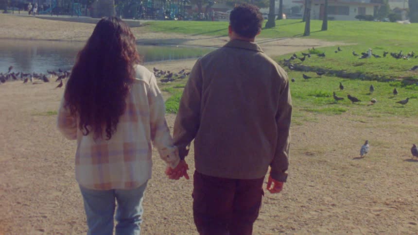 A man and woman walking holding hands near a lake