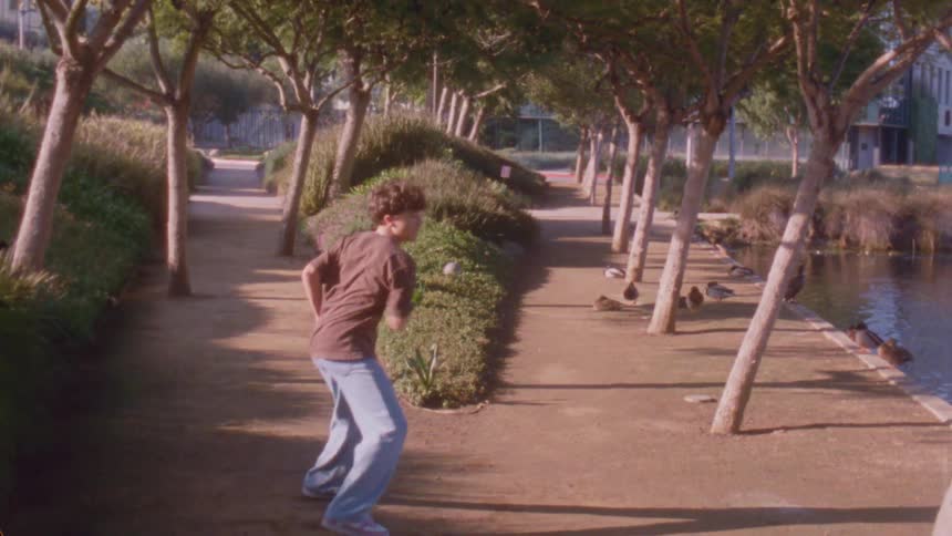 A young male teen dancer dancing outdoors on a walkway in a city during daytime