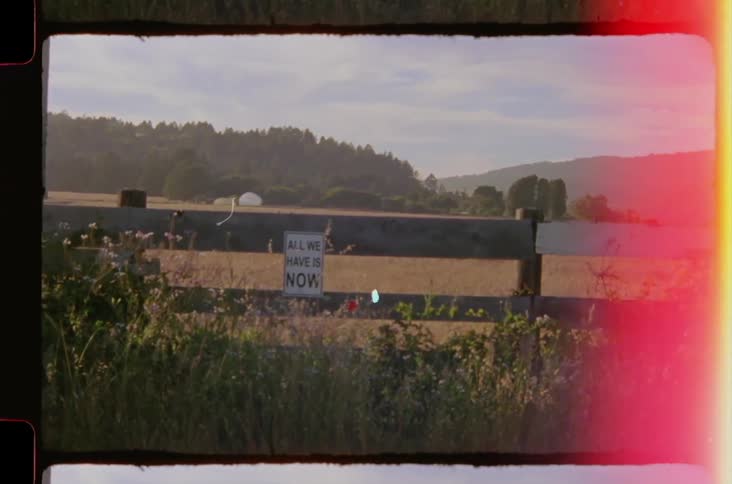 Wooden fence in a vast field with trees in the background