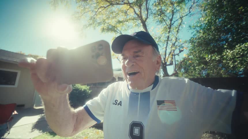 A man cheering while looking at a smartphone