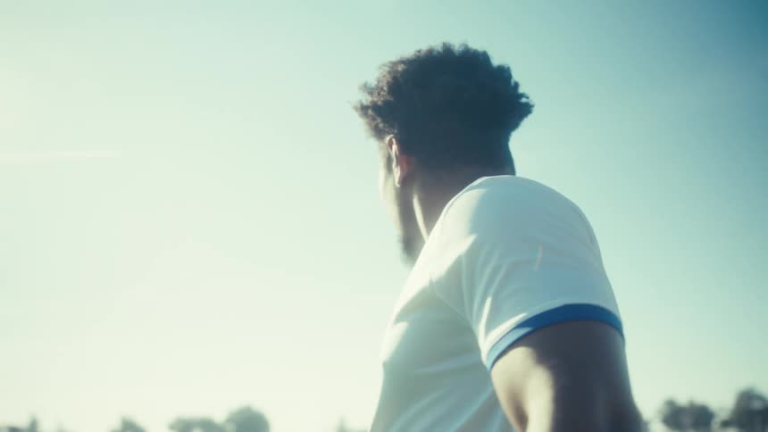 Man clenches a fist after kicking a ball on a sunny summer day