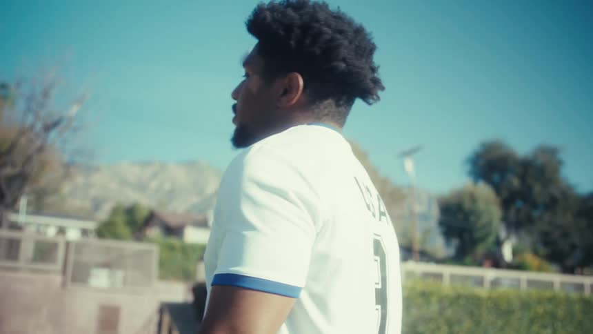 Man in a sports shirt is walking outdoors with a happy expression