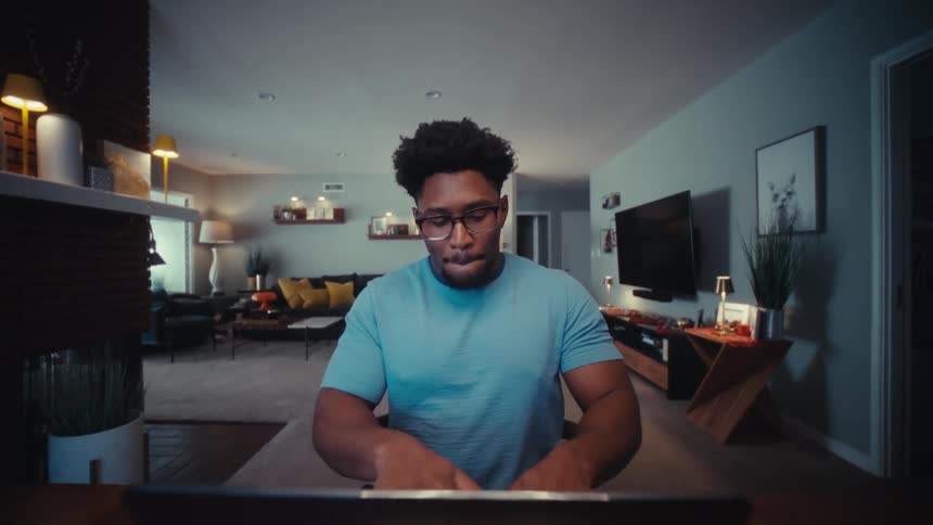 Man is sitting down opening his laptop and starting to type