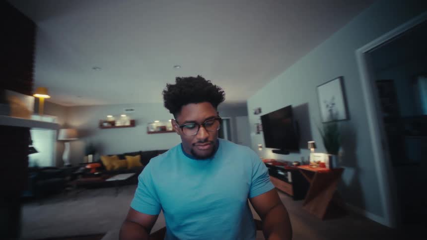 A man works on a laptop while sitting at a table in a modern living room
