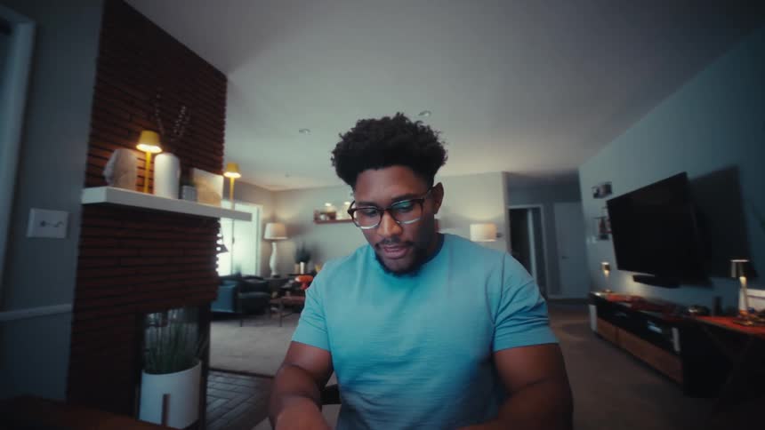 Man sits at a table pushing buttons on his laptop computer keyboard