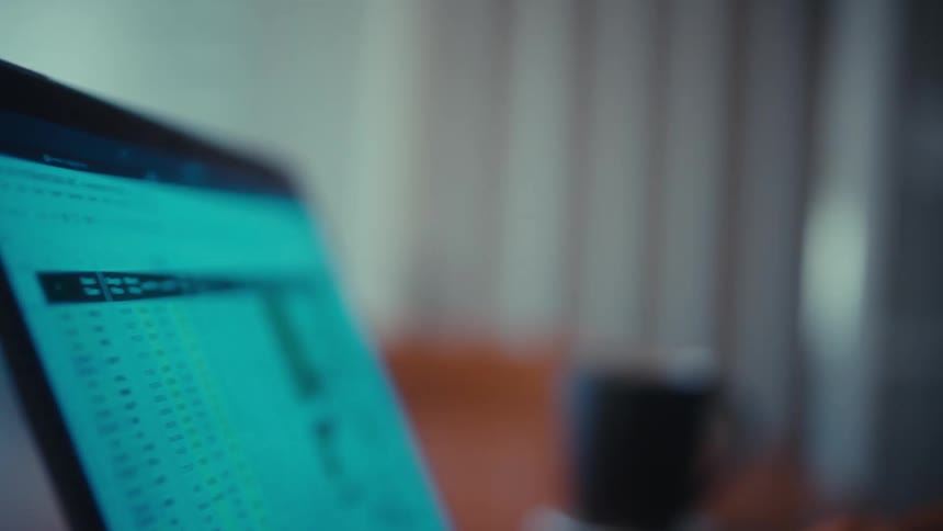 Close up of a young black man working with a laptop computer while sitting at a table indoors during daytime