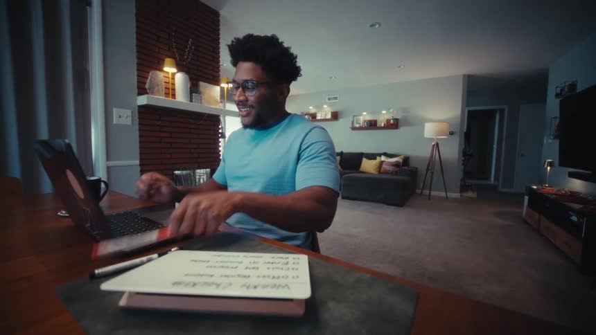 A man checks off tasks on a to do list while working at a desk in a modern living room