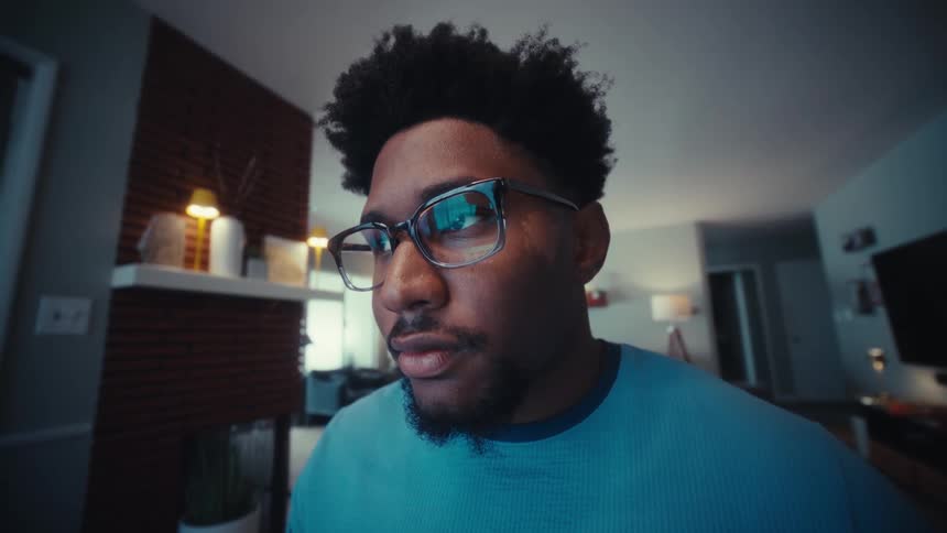 A young black man working with a laptop computer while sitting at a table indoors during daytime