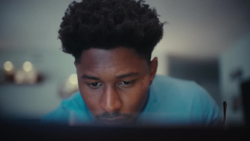 The man puts his glasses on while looking at a computer