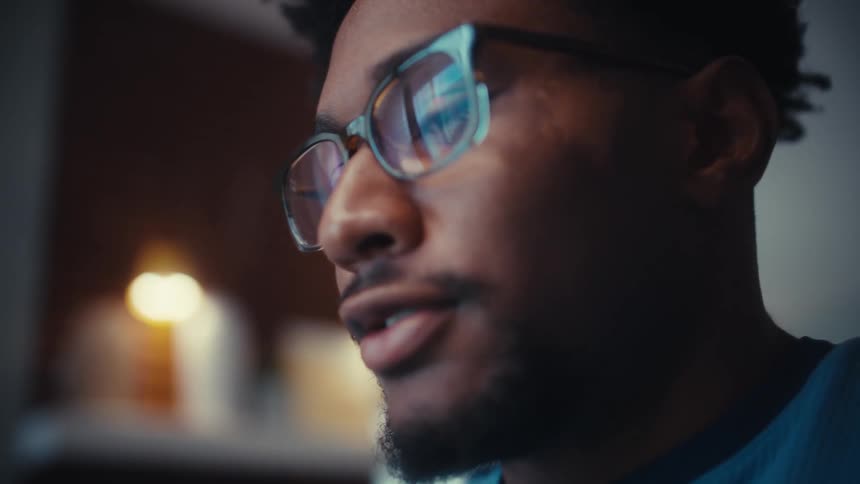 Man with glasses typing on a calculator