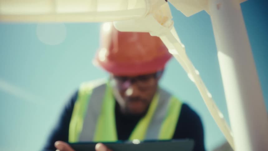 Close up of a young black male engineer working with a plastic mini windmill outdoors during daytime