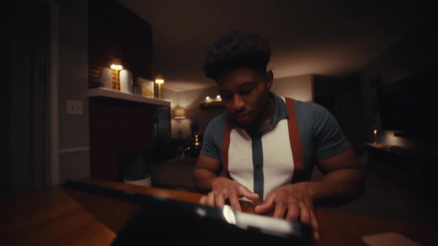Man sitting at a table typing on a keyboard with a tablet computer