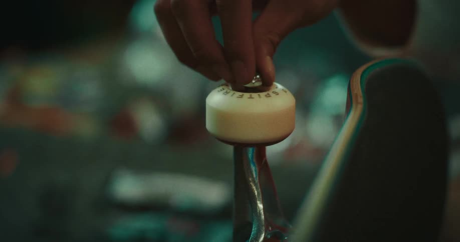 Male hands installing and screwing a wheel on a skateboard indoors