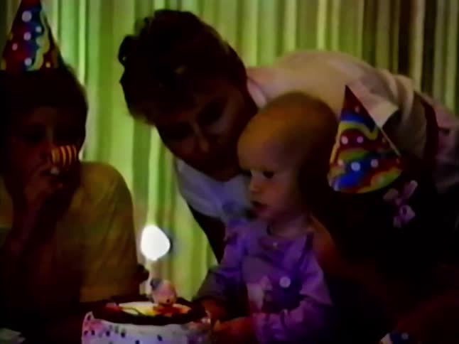 The baby blows out the candle on the birthday cake