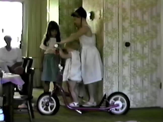 Girls playing on a scooter inside a house