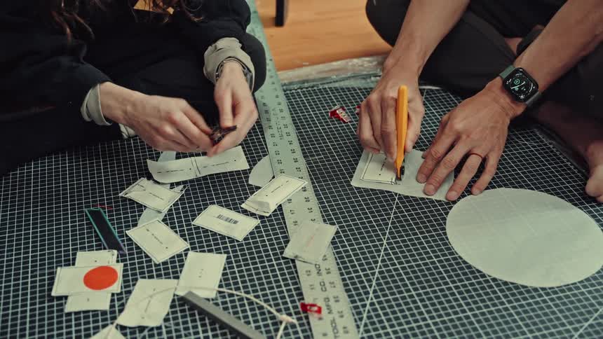 Two tailors are using their tools and measuring