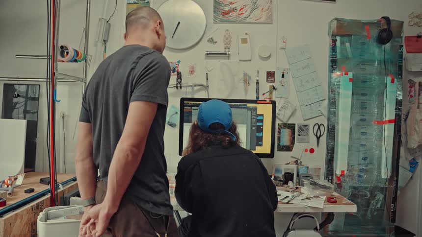 Two two people look at the computer screen in the workshop