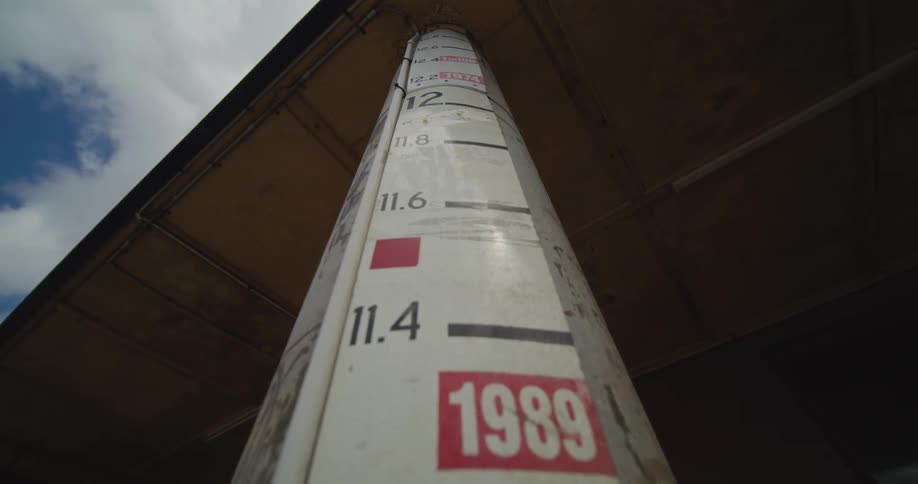 A building pillar stands in the bright midday sun covered with a series of posters layered across its surface each one catching the clear daylight