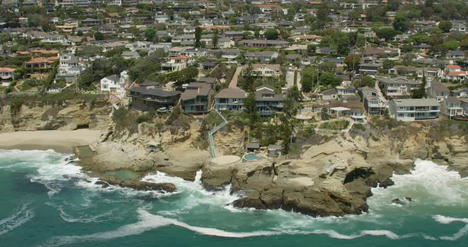The waves crash against the shore near houses in San Diego, California