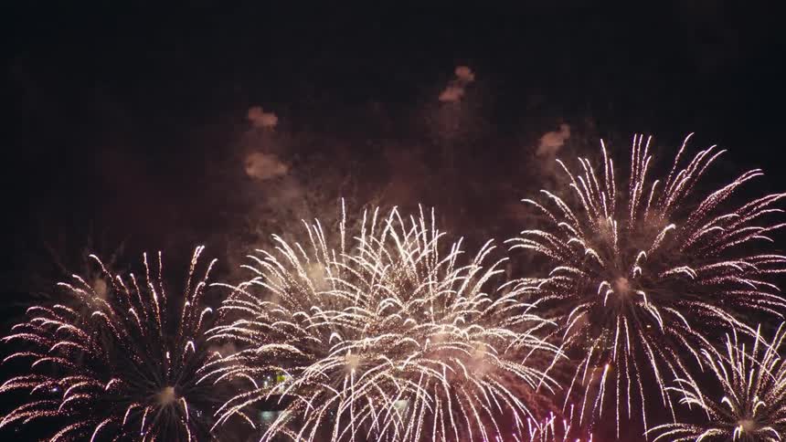 Fireworks explode in the sky over the water at night during a fireworks display