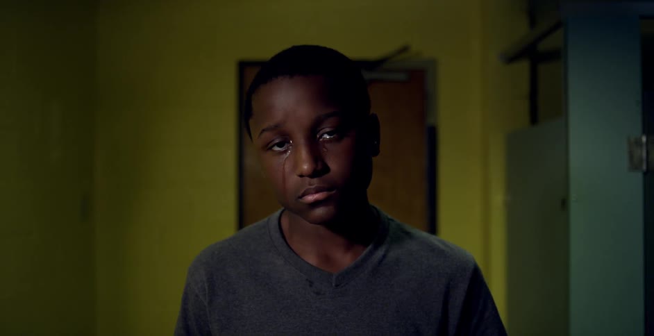 A young man standing in a room crying