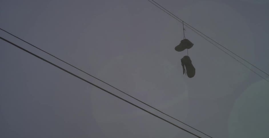 Sneakers hanging on an electrical cable on a rainy day