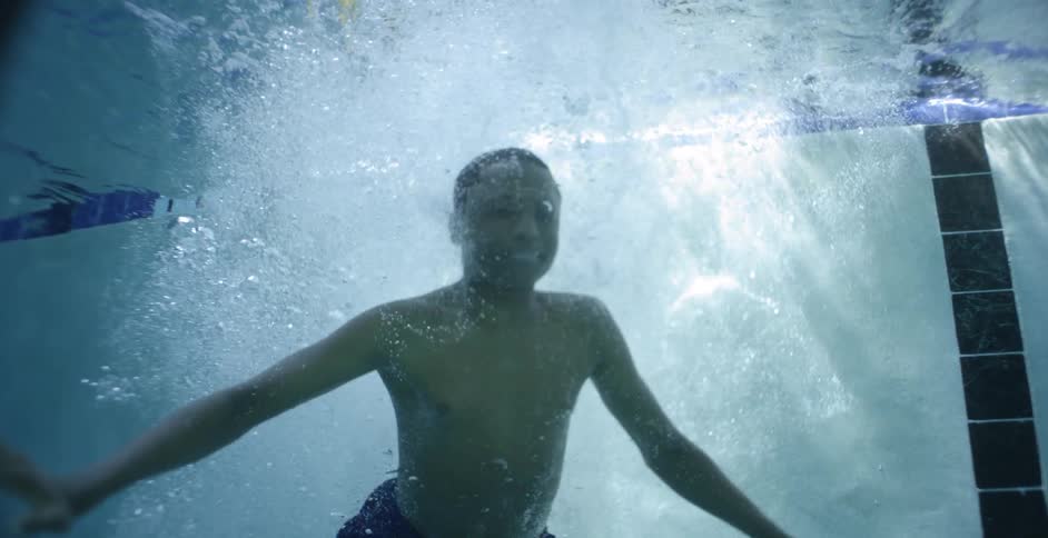 A boy jumps into a swimming pool