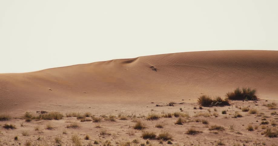 A large sand dune is under the cloudy sky