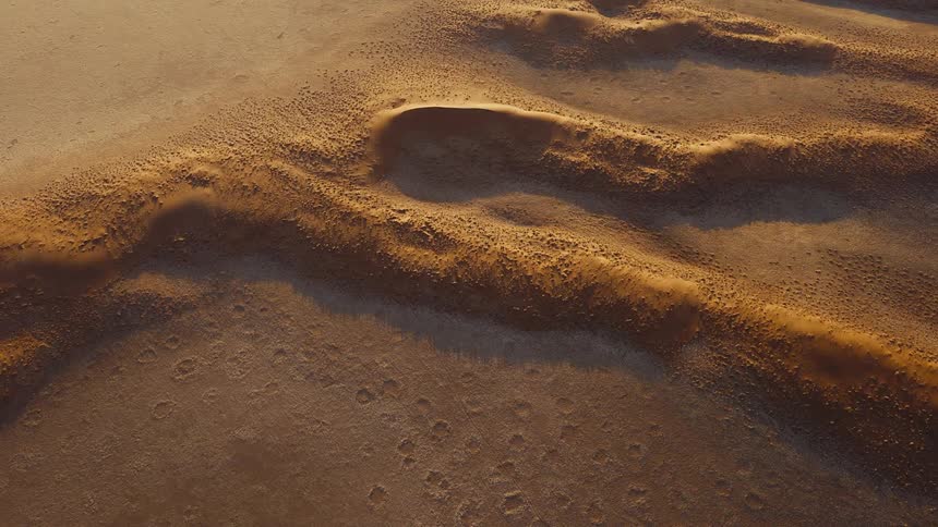 Human footprints imprinted in the sand with relief emphasized by side lighting