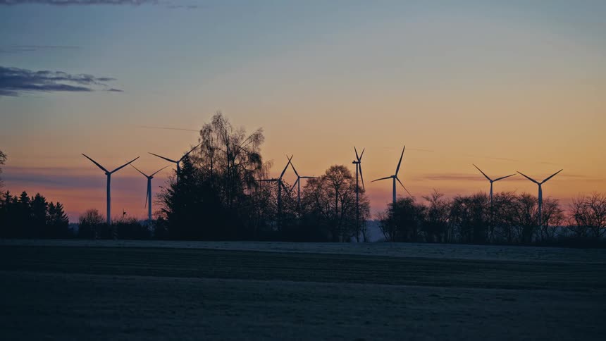 Turbines spinning on a wind farm above the trees